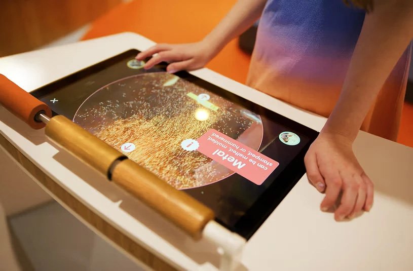 Visitors interacting with a museum touchscreen exhibit.